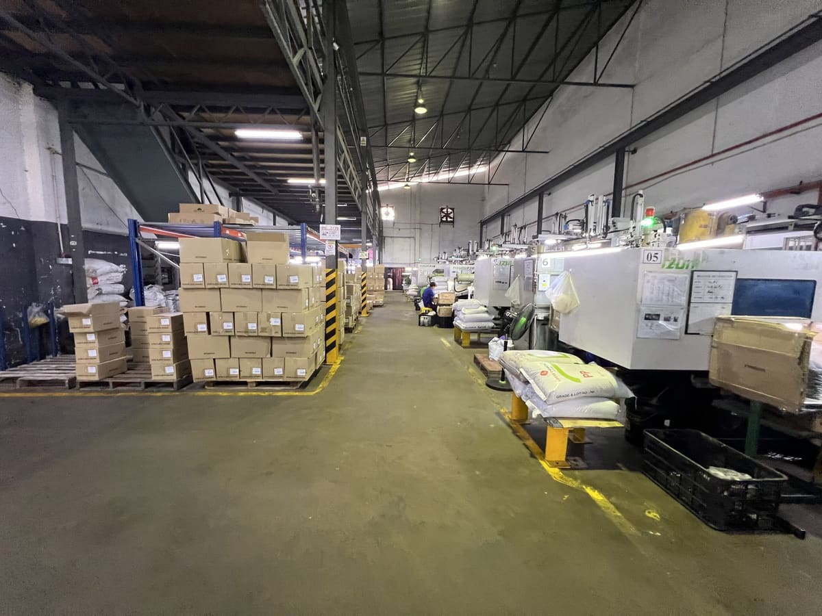 Machine aisle with finished goods cartons and raw material staged beside each press
