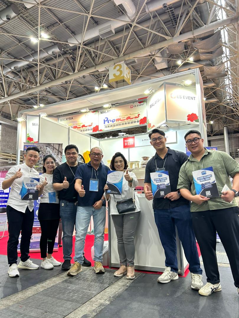 Group photo of the B-PEN team with visitors in front of the booth